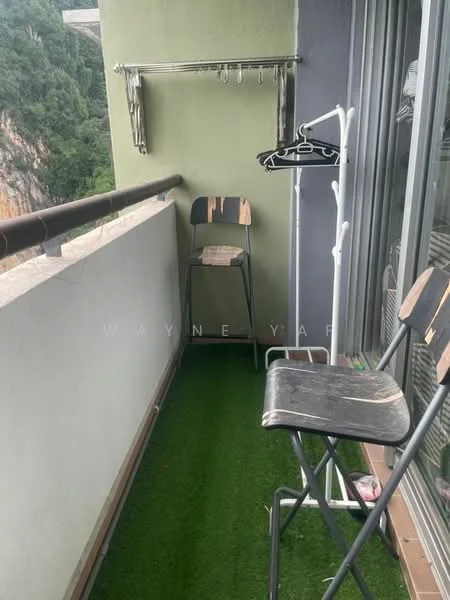 Balcony features: artificial grass flooring, railing with brown finish, two metal bar stools, clothes drying rack, clothes hanger, green painted walls.