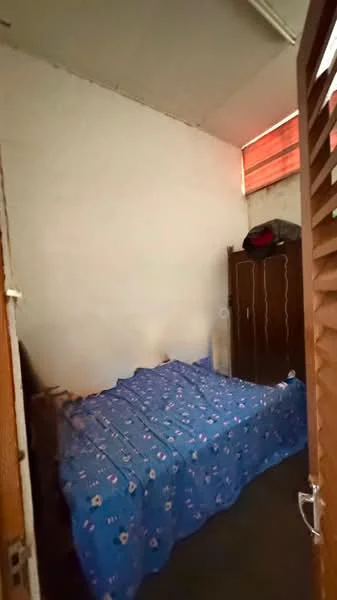 Bedroom features: single bed with blue bedding, wooden wardrobe, white painted walls, window with wooden slats, flooring not visible.