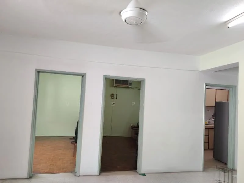 Room features: white painted walls, ceiling with light fixture, wooden flooring, door frames in green, open layout, visible doorways to adjacent rooms, no visible furniture, neutral color scheme.