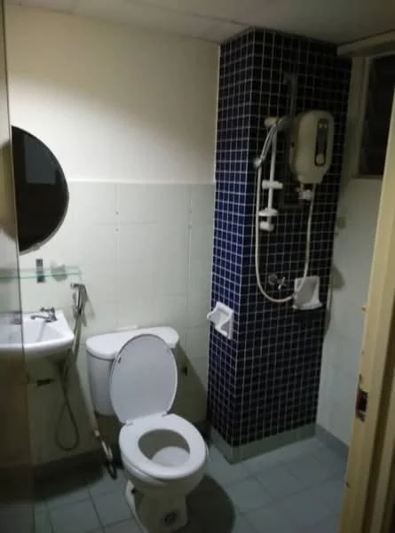 Bathroom features: white ceramic toilet, round mirror, blue tiled accent wall, white tiled walls, shower with wall-mounted water heater, handheld shower, sink with faucet, grey floor tiles.