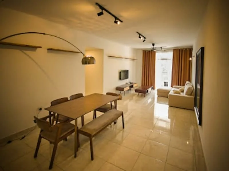 Living features: white painted walls, glossy tile flooring, recessed downlights, 5-blade ceiling fan, large window with sheer curtains, sofa in light fabric, wooden coffee table, TV console, wall-mounted TV, dining table with wooden surface, wooden bench seating, decorative wall shelves; style: modern.