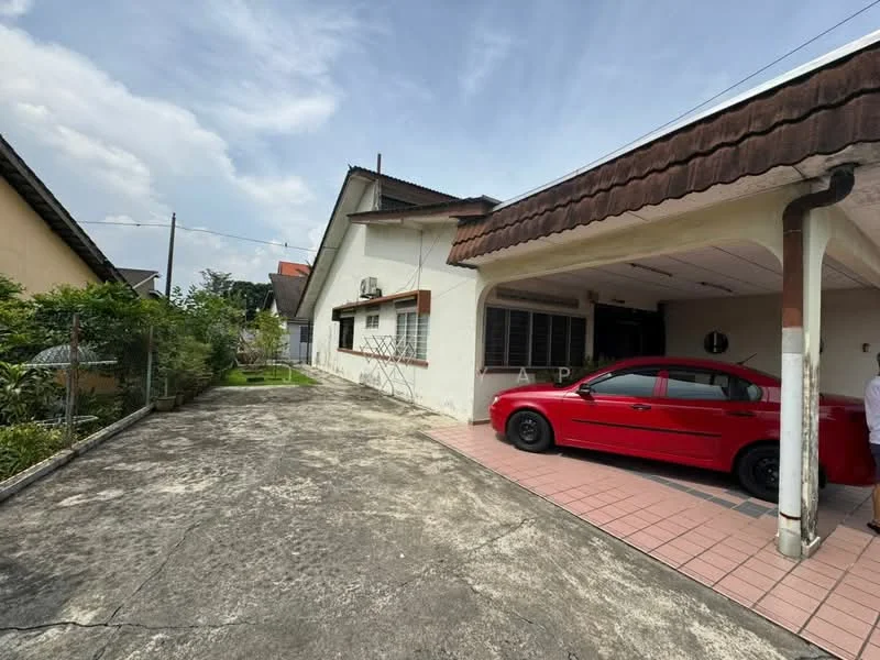 Exterior type: detached bungalow; features: single-storey, car porch with awning, red car parked in driveway, paved driveway, manicured lawn, fenced yard, exposed concrete surface, roof with overhang, air conditioning unit visible on wall, garden area with greenery; style: traditional.