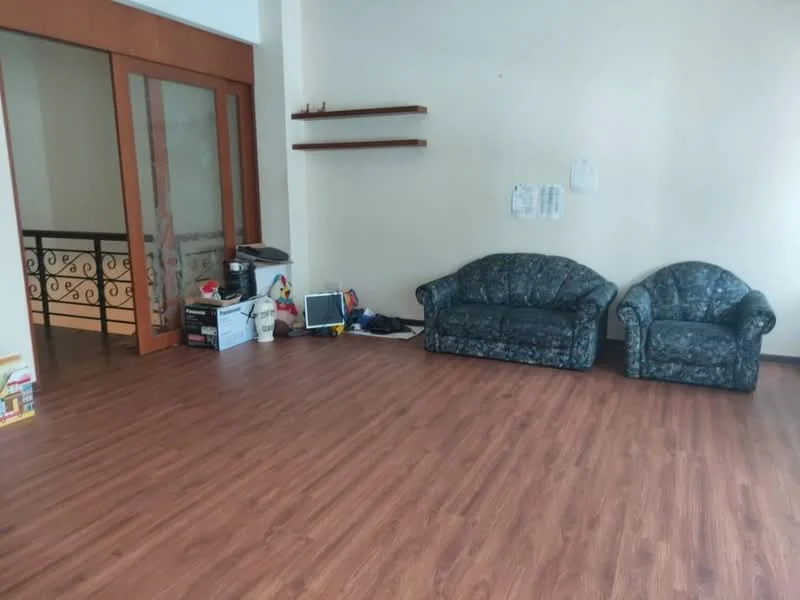 Living features: laminate wood flooring, two fabric sofas in blue floral pattern, open shelving unit on wall, wall-mounted TV console, large windows with natural light, neutral painted walls, decorative railing visible in background, space for additional furniture; style: modern.