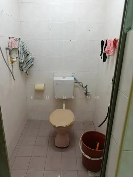 Bathroom features: white tiled walls, light grey tiled flooring, one-piece toilet, toilet paper holder, sink with faucet, bucket, hanging towels, wall-mounted mirror.