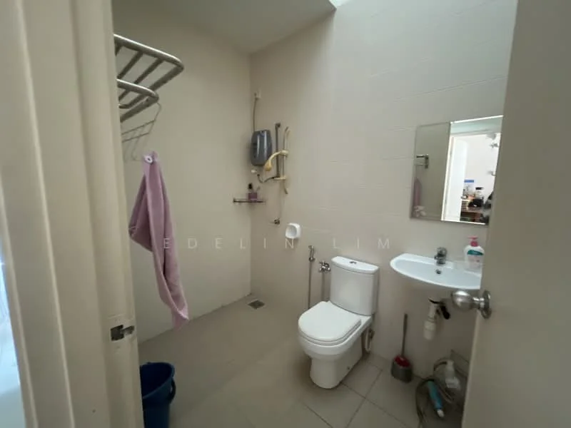 Bathroom features: white tiled walls, light grey floor tiles, one-piece toilet, small wall-mounted sink, framed mirror, shower head with wall-mounted holder, towel rack, hanging towel, plumbing fixtures visible, bucket, cleaning supplies, toilet paper holder.