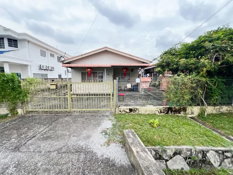 Exterior type: detached bungalow; features: single-storey, grey painted facade, red tiled roof, front yard with grass, fenced perimeter, gate at entrance, mature trees, decorative lanterns, concrete driveway, surrounded by greenery; style: traditional.