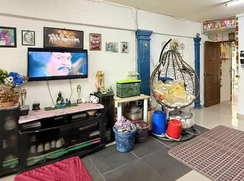 Living features: black TV console, flat-screen TV, wall-mounted TV, decorative wall art, blue accent wall, grey floor tiles, hanging rattan chair, fish tank, various decorative items, area rug with geometric pattern, storage baskets, wooden door, wall-mounted shelves; style: contemporary.