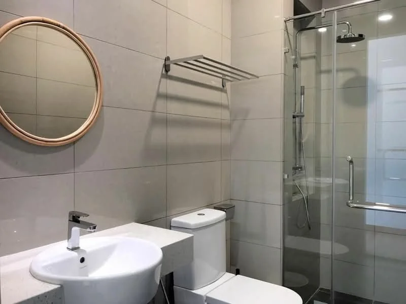 Bathroom features: white ceramic sink, chrome basin mixer faucet, white one-piece toilet, glass shower enclosure, rain shower head, handheld shower, light grey tiled walls, light grey tiled flooring, round mirror, towel rack, wall-mounted grab bar; style: modern.