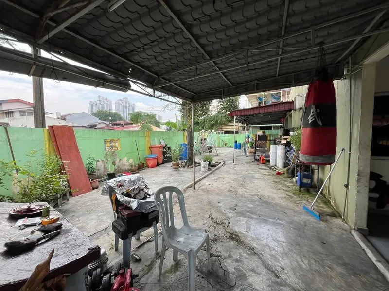 Exterior features: concrete flooring, green painted walls, covered patio area, boxing bag hanging, outdoor furniture, gardening pots, various tools and equipment, surrounding greenery, urban skyline in background.