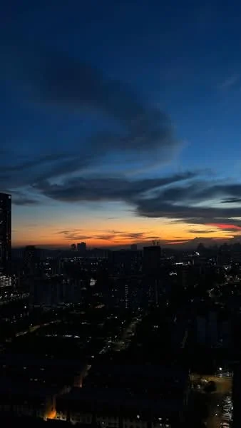 Exterior type: high-rise condominium; features: city skyline view, sunset, cloudy sky, illuminated buildings, urban landscape; style: modern.