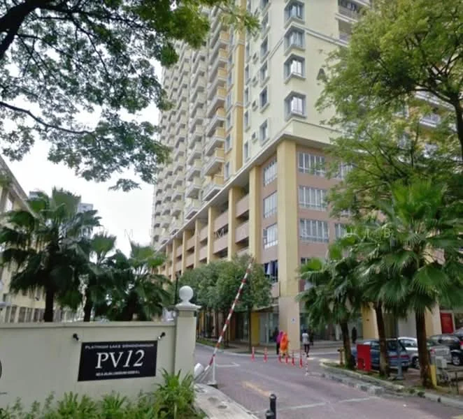 Exterior type: mid-rise condominium; features: yellow painted facade, glass windows, palm trees in landscaping, manicured lawn, security gate at entrance, driveway with interlocking pavers, surrounded by greenery; style: modern.
