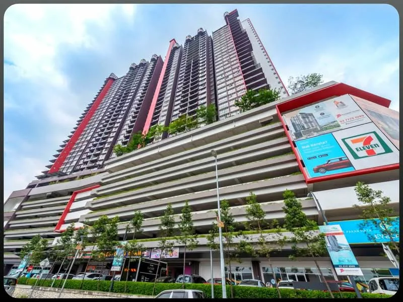 Exterior type: high-rise condominium; features: glass curtain wall, red accent panels, multi-storey car park, retail spaces at ground level, landscaped greenery on terraces, balconies on upper floors, signage for retail outlets, surrounded by urban context; style: modern.