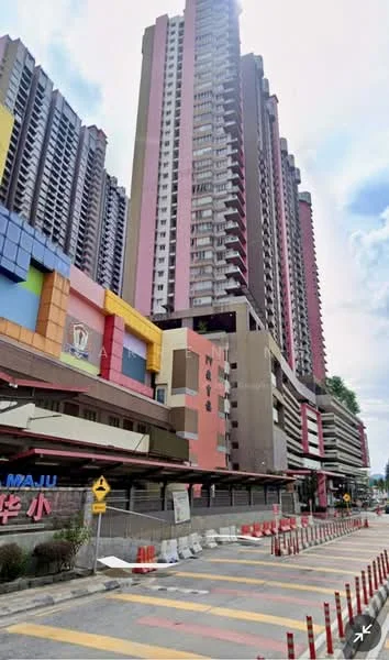 Exterior type: high-rise condominium; features: multi-storey building, colorful facade with pink, yellow, and blue elements, balconies on multiple floors, commercial space at ground level, surrounding road with traffic barriers, urban setting with nearby infrastructure; style: modern.