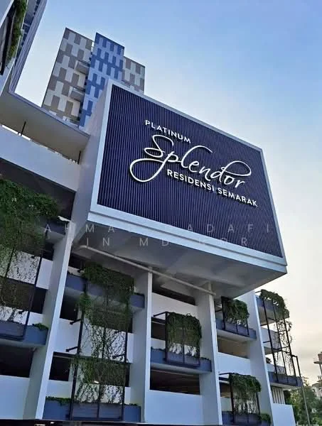 Exterior type: high-rise condominium; features: glass curtain wall, white painted facade, greenery on balconies, signage with name 'Platinum Splendor Residensi Semarak', modern architectural design, multiple levels, projecting balconies, feature lighting, urban context; style: modern.