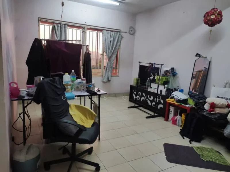 Room features: tiled flooring, white painted walls, curtains on windows, clothes drying rack, office chair, desk with clutter, various items on floor, wall clock, plastic bottles, laundry basket.