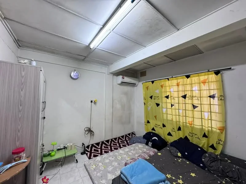 Bedroom features: white painted walls, dropped ceiling, tile flooring, 2 single beds with bedding, yellow curtains with geometric pattern, 1 wall-mounted split AC, wardrobe with grey finish, small side table, decorative rug, wall clock, light fixture.