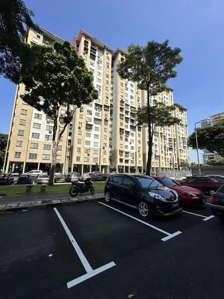Exterior type: mid-rise condominium; features: yellow painted facade, multiple storeys, balconies on upper floors, large windows, surrounded by trees, parking lot in foreground, cars parked in designated spaces, manicured lawn, urban setting; style: modern.