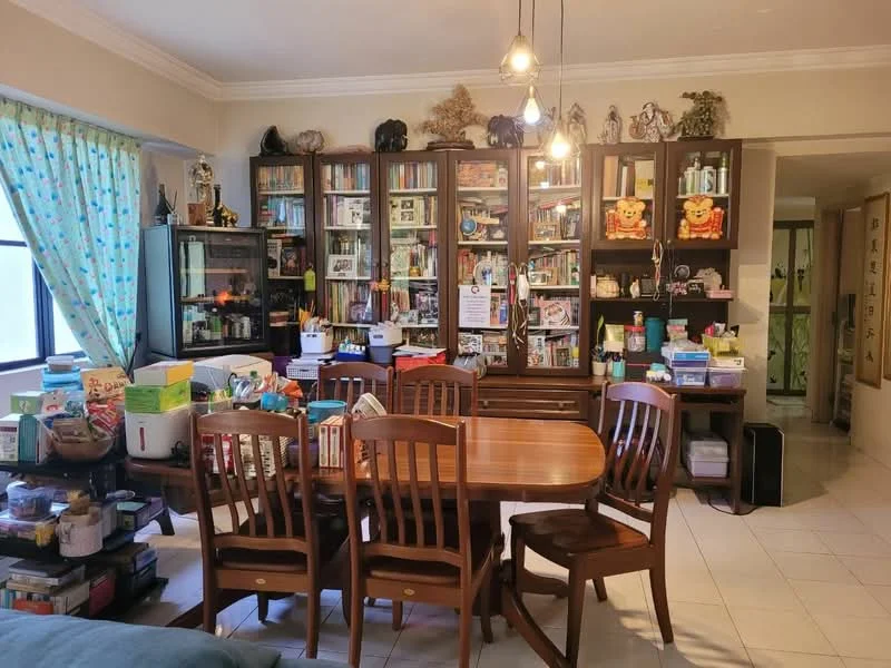 Dining features: wood dining table, 6 wooden dining chairs, bookshelves with various items, glass display cabinet, decorative figurines, green sheer curtains, tile flooring, ceiling lights, wall-mounted decorations, open space leading to another room; style: traditional.