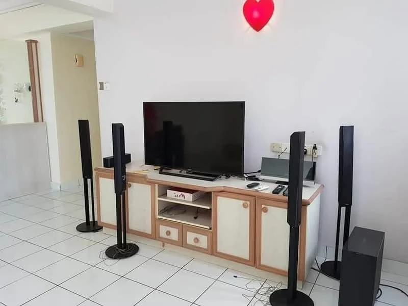 Living features: white painted walls, white tiled flooring, black flat-screen TV, wooden TV console with drawers, two tall black speakers on stands, black subwoofer, cable management visible, red heart-shaped wall light; style: modern.