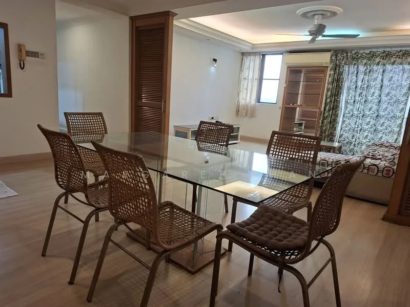 Dining features: glass dining table, 6 woven dining chairs, light wood flooring, white painted walls, ceiling fan with light, large window with sheer curtains, decorative wall panel, open layout to living area; style: modern. Living features: sofa bed, wooden shelving unit, large window with patterned curtains, decorative throw pillows, area rug, light wood flooring; style: modern.