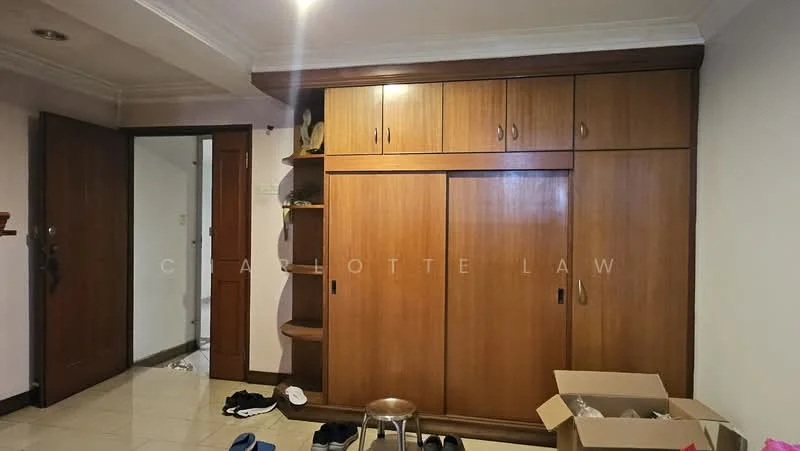 Room features: wooden cabinetry with multiple doors, cream painted walls, tile flooring, ceiling with crown moulding, door leading to another room, box of items on the floor, stool, shoes scattered on the floor.