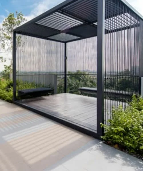 Exterior features: open pavilion structure, metal frame, wooden decking, surrounding greenery, landscaped garden, glass panels, shaded seating area; style: modern.
