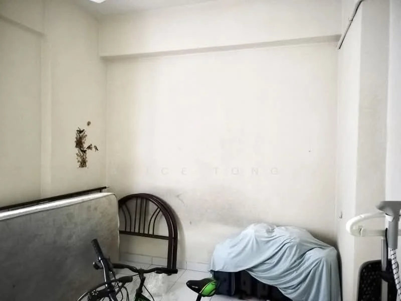 Room features: white painted walls, tile flooring, bicycle, mattress, blanket, furniture with fabric cover, visible wall damage.