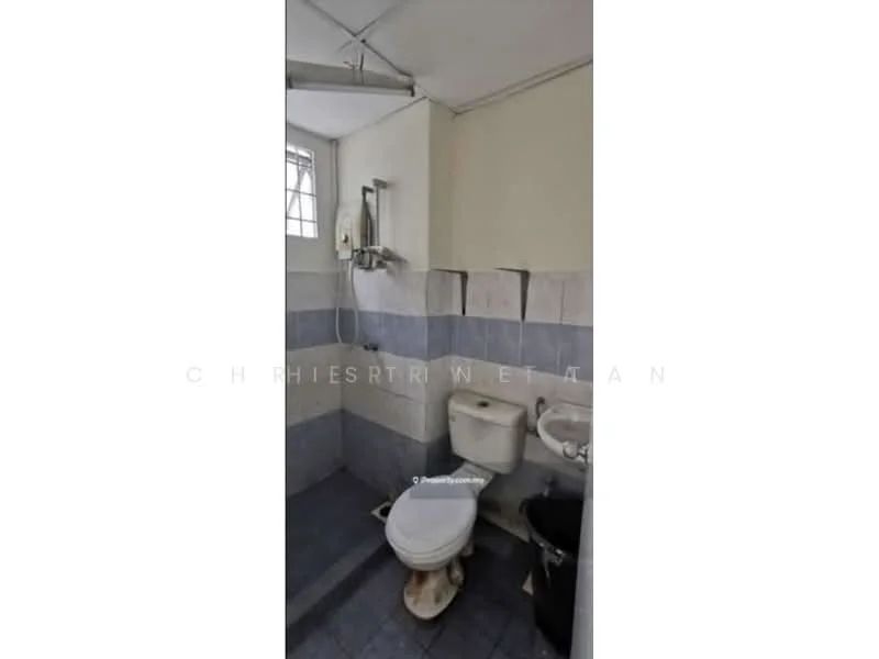Bathroom features: white toilet, shower with handheld showerhead, grey tiled walls, blue tiled flooring, sink with faucet, window for natural light, exposed plumbing, wall-mounted mirror.