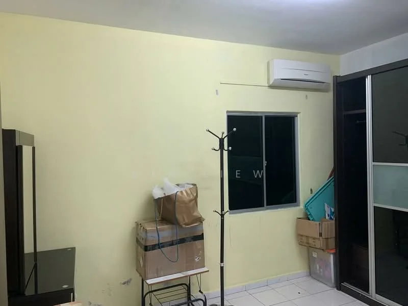 Room features: yellow painted walls, white ceiling, tile flooring, window with metal frame, wall-mounted split AC, clothes rack, small table, cardboard boxes.