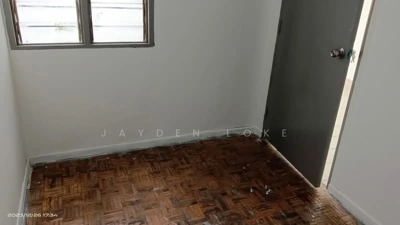 Room features: wooden flooring, white painted walls, single window with grey frame, grey door, baseboard, corner of room visible.