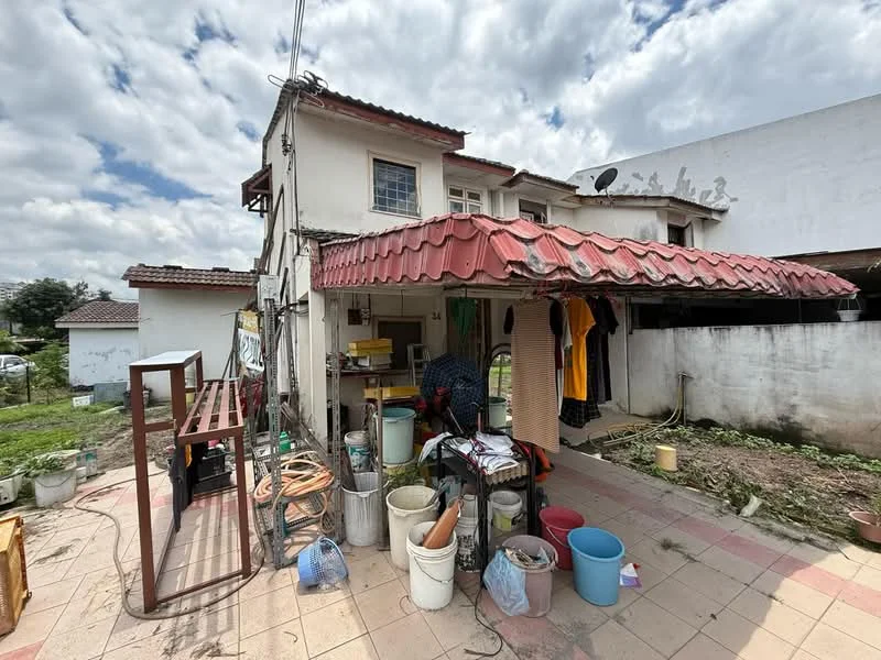 Exterior type: detached bungalow; features: red tiled roof, white painted facade, outdoor storage area, paved outdoor flooring, various plastic containers, clothes hanging on a line, garden area with grass, adjacent building visible, utility poles, partially covered outdoor space; style: traditional.