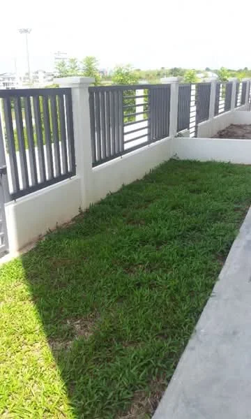 Exterior features: green grass lawn, concrete pathway, metal railing, white painted wall, fenced perimeter, sunny outdoor area; style: modern.