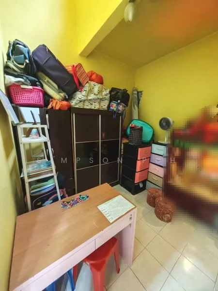Room features: yellow painted walls, tile flooring, wooden desk, red plastic chair, black wardrobe, pink storage drawers, stacked bags and luggage, standing fan.