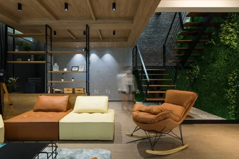 Living features: L-shape sectional sofa in beige and brown, rocking chair in orange leather, wooden ceiling with recessed lighting, exposed brick wall, green vertical garden, wooden staircase with metal railing, decorative shelving unit, stone flooring, wall-mounted lighting, decorative items on shelves; style: modern.