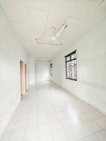 Room features: light green painted walls, white tiled flooring, ceiling fan, two windows with metal grilles, plain ceiling, no visible furniture, neutral decor, long rectangular layout; style: minimalist.
