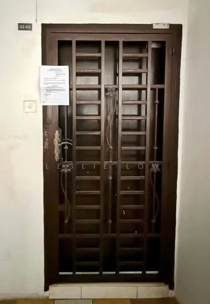 Room features: brown metal security door, grill design, door handle, lock mechanism, attached notice or document, light switch, wall with paint, floor tiles.