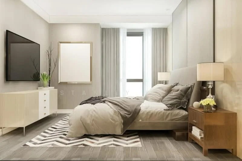 Bedroom features: king-size bed with grey bedding, upholstered headboard, 2 bedside lamps with fabric shades, wooden nightstand, white dresser with drawers, wall-mounted flat-screen TV, framed artwork on wall, area rug with geometric pattern, floor-to-ceiling windows with sheer curtains, wooden flooring, decorative plant on nightstand; style: modern.