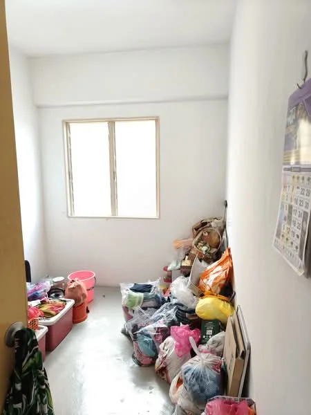 Room features: white painted walls, concrete flooring, single window, various bags and containers, cluttered space.