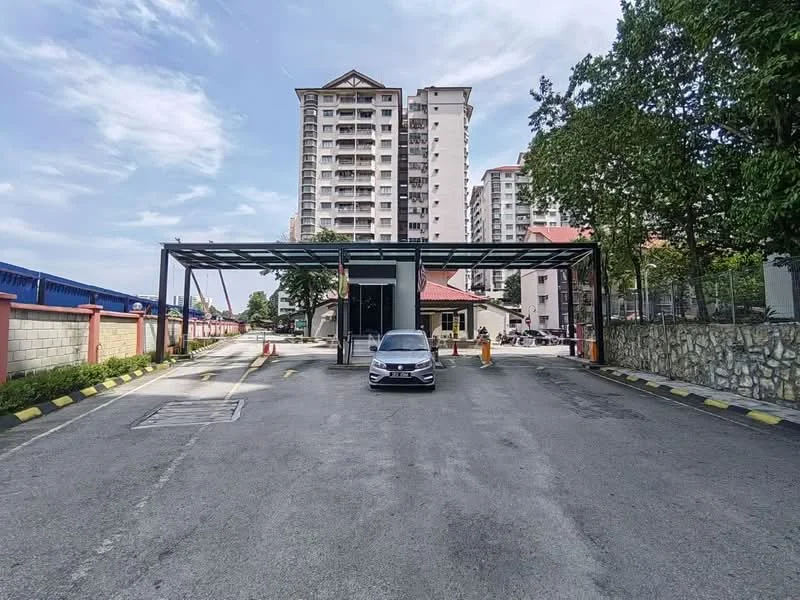 Exterior type: mid-rise condominium; features: covered parking area, guard house at entrance, paved driveway, surrounded by greenery, multiple-storey residential buildings in background, clear blue sky; style: modern.