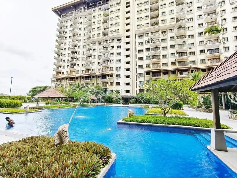 Exterior type: high-rise condominium; features: infinity pool, pool deck with loungers, landscaped garden with shrubs, water feature with fish sculptures, surrounding greenery, multiple storeys, balconies on upper floors; style: modern.