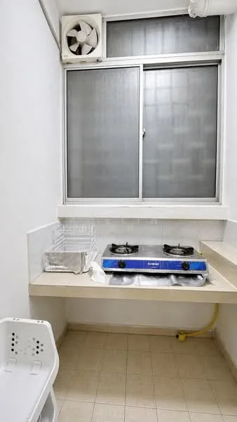 Laundry features: 2-burner gas hob, white tiled backsplash, grey countertop, window with frosted glass, wall-mounted exhaust fan, white plastic laundry basket, light beige tiled flooring.