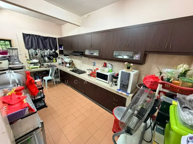 Kitchen features: brown wooden cabinetry, white tiled backsplash, ceramic tile flooring in orange, built-in gas stove, microwave, refrigerator, kitchen sink, countertop with appliances, wall-mounted exhaust hood, multiple kitchen utensils and appliances visible, open shelving, small fan.