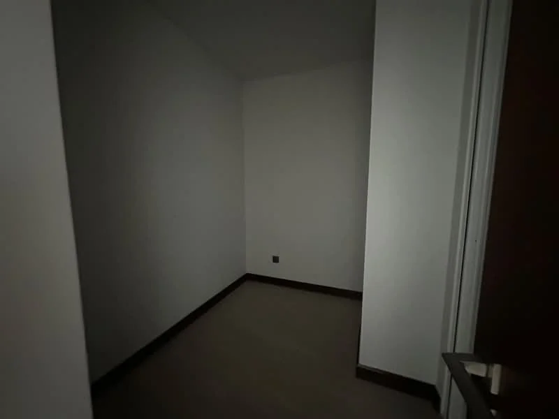 Room features: white painted walls, light wood flooring, corner room, no visible windows, minimal decor.