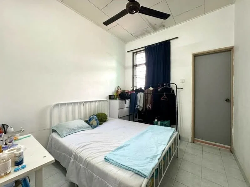 Bedroom features: single bed with white metal frame, blue and green decorative pillow, white walls, ceiling fan, window with blue curtains, light grey tiled flooring, built-in wardrobe with grey door, clothes rack with hanging clothes, small white bedside table, bottle and container on bedside table; style: minimalist.