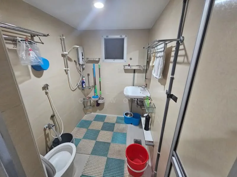Bathroom features: white toilet, sink with wall-mounted faucet, shower with handheld showerhead, tiled walls in beige, tiled flooring in blue and green, window for natural light, metal towel rack, plastic bucket, cleaning supplies on rack, shower curtain rod, wall-mounted mirror.