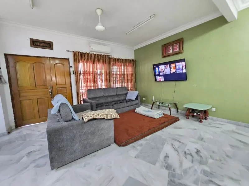 Living features: grey fabric sofa, area rug in brown, wall-mounted TV, wooden door, curtains in brown, ceiling fan, marble flooring, green accent wall, glass coffee table, decorative wall frame; style: modern.