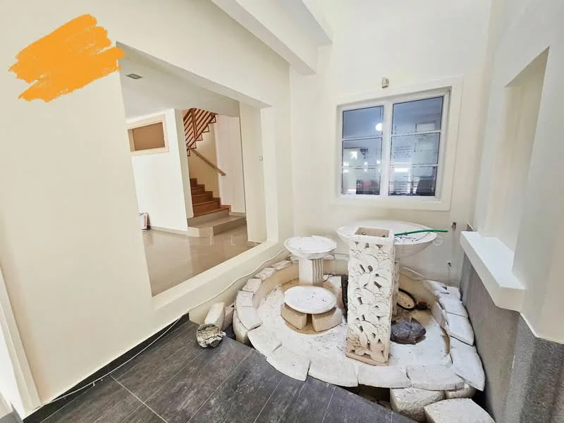 Room features: white painted walls, grey tile flooring, decorative stone fountain, circular stone base, natural stone pebbles, large window with white frame, staircase visible in background, open layout; style: modern.