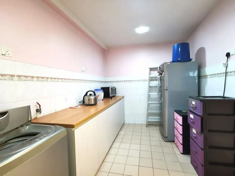 Kitchen features: pink painted walls, white tiled backsplash, laminate countertop, stainless-steel sink, built-in washing machine, freestanding refrigerator, microwave, kettle, metal shelving unit, plastic storage drawers, tile flooring, ceiling light.