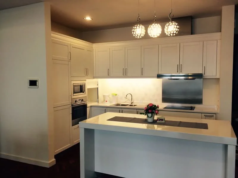 Kitchen features: white shaker cabinets, stainless-steel built-in oven, stainless-steel microwave, stainless-steel range hood, stainless-steel cooktop, quartz countertop, white backsplash, pendant lights, single-bowl stainless-steel sink, chrome pull-down faucet, kitchen island, decorative flower arrangement; style: modern.