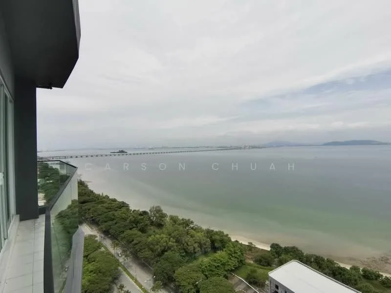 Exterior type: high-rise condominium; features: balcony with glass railing, sea view, landscaped greenery below, view of bridge in distance, cloudy sky, waterfront location; style: modern.